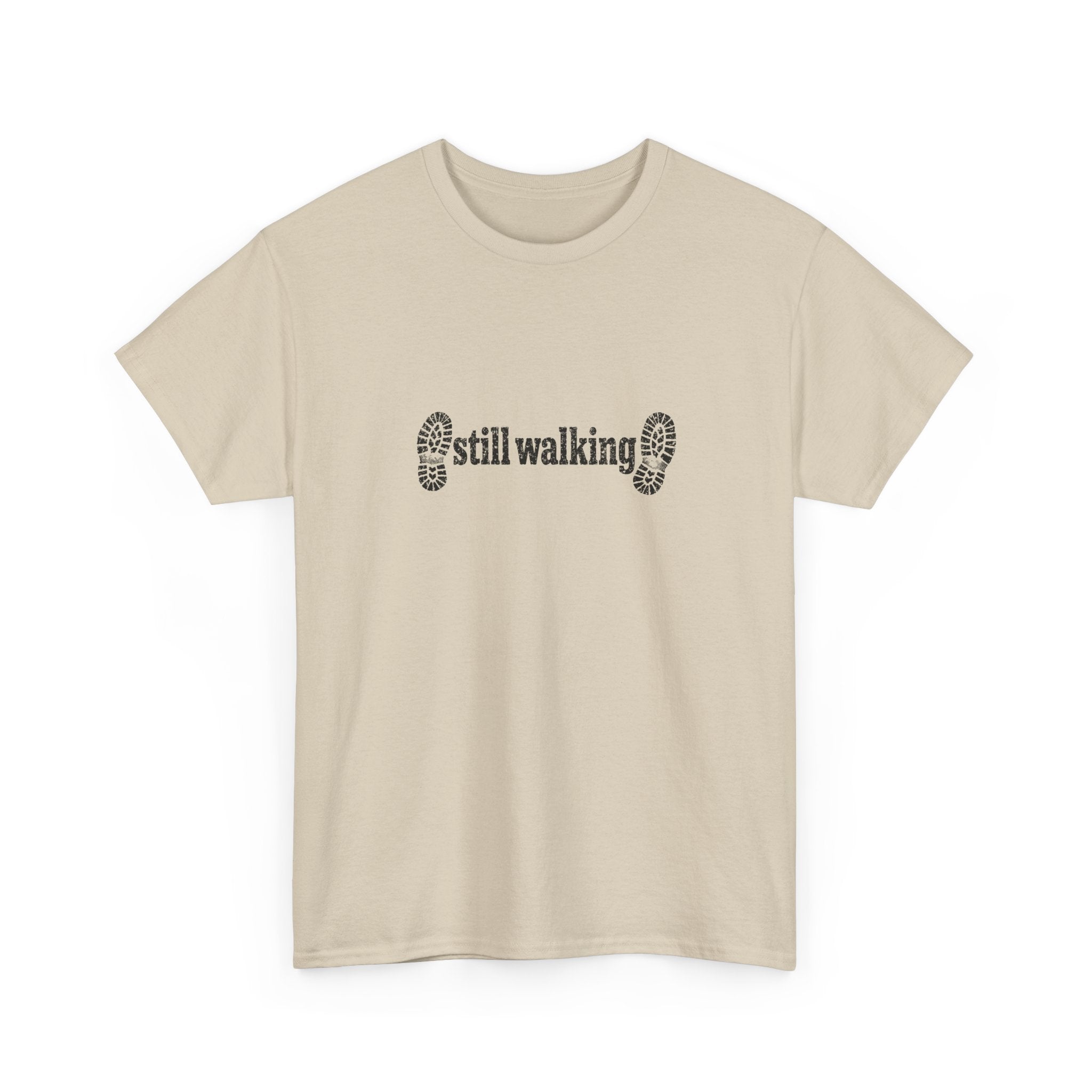 Beige t-shirt with 'still walking' text and footprints on a white background