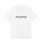 White t-shirt with 'still growing' text on a white background