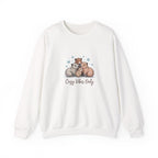 Cute illustrated family of capybaras cuddling together with snowflakes and the text ‘Cozy Vibes Only,’ cozy winter animal art.